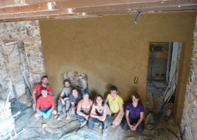 Photo de l'équipe devant le mur couvert de l'enduit terre de 3 à 5 cms.