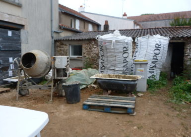 Installation du chantier. Poste malaxage de l'enduit proche de la maison et du tas de terre